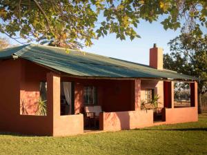 una pequeña casa roja con techo verde en Thaba Manzi Ranch, en Magaliesburg