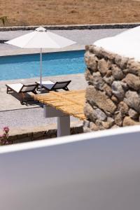 a table with two chairs and an umbrella next to a pool at Archon Seaside Retreat in Plaka