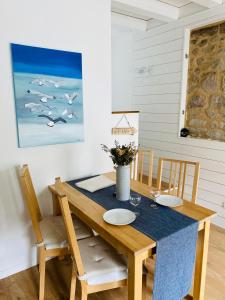 une salle à manger avec une table, des chaises et un tableau dans l'établissement Chaumière des Dunes à 350m de la plage de Kerhillio, à Erdeven