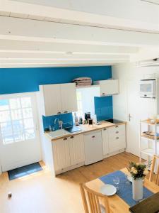 une cuisine avec des placards blancs et un mur bleu dans l'établissement Chaumière des Dunes à 350m de la plage de Kerhillio, à Erdeven