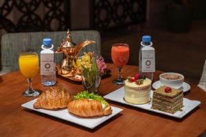 a wooden table with two plates of food and drinks at Aram Hotel - AlMeshael Exit 18 in Riyadh