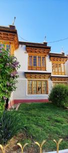 Casa grande con ventanas de madera y patio verde. en Hotel Royal Plaza, en Leh