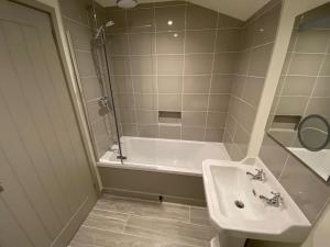 a bathroom with a sink and a bath tub at Glebe Barn, Little Glebe Farm in Cheltenham