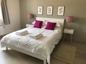 um quarto com uma grande cama branca com almofadas cor-de-rosa em Glebe Barn, Little Glebe Farm em Cheltenham