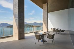 a balcony with tables and chairs and a view of the water at Yeosu Belle Mer in Yeosu
