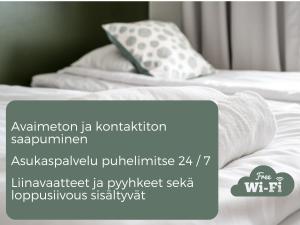 una foto de una cama con sábanas y almohadas blancas en Hiisi Hotel Lohja, en Lohja