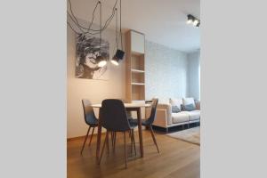a dining room with a table and chairs and a couch at Diagonala 2 in Novi Sad