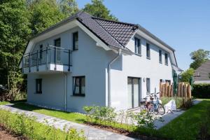 a white house with a balcony and a bike at Dünenquartier - Apartment 01 in Zingst