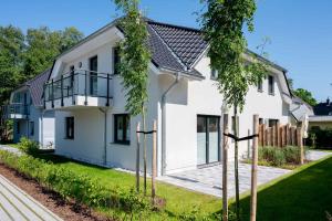 a white house with trees in front of it at Dünenquartier Apartment 26 in Zingst
