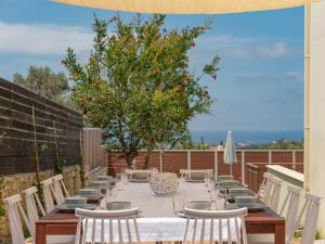 een lange tafel met witte tafelkleden en stoelen op een patio bij Family Villa Rousa in Rethymno with Pool, BBQ and Kids Area in Loutra