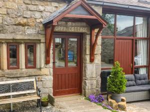 a coffee shop with a red door and a bench at Poppy Cottage in Settle