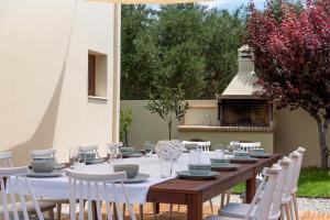 een houten tafel met witte stoelen en een tafel met borden en kommen bij Family Villa Rousa in Rethymno with Pool, BBQ and Kids Area in Loutra
