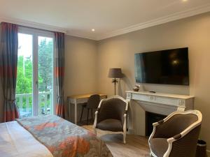 a bedroom with a bed and a fireplace with a television at Villa Augeval Hôtel de charme & Spa in Deauville