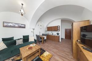 ein Wohnzimmer mit einem grünen Sofa und einer Küche in der Unterkunft PB Apartments in Spišská Nová Ves
