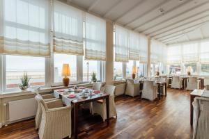 a dining room with tables and chairs and windows at Strandhotel Hohenzollern in Borkum