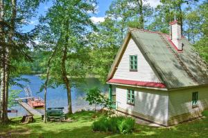 uma casa na margem de um lago com um barco em Lauryno sodyba em Suviekas