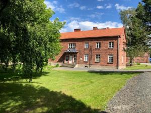a large brick building with a lawn in front of it at Hotelli Verstas in Nakkila