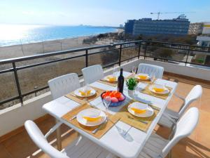 una mesa con sillas blancas y vistas a la playa en GMID IMMO Apartamento Oasis Atico, en Roses