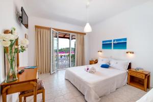a bedroom with a bed and a desk and a window at Niko's Studio Apartments with terrace in Gaios