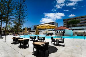 ein Pool mit Tischen und Sonnenschirmen neben einem Pool in der Unterkunft Rey Carlos in Playa del Ingles