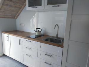 a kitchen with white cabinets and a sink at Apartament z tarasem in Stegna