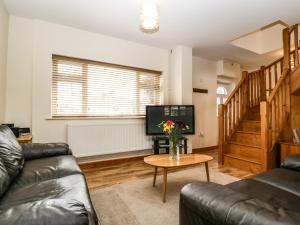 uma sala de estar com um sofá e uma mesa com uma televisão em Muskoka Lodge em Midsomer Norton