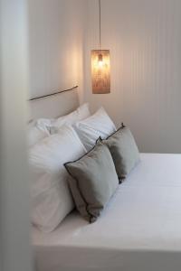 a white bed with white pillows and a light at Archon Seaside Retreat in Plaka