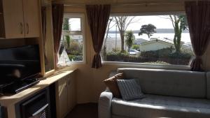a living room with a couch and a large window at Pine Ridge 59 Rockley Park Poole with sea view sleeps six in Poole