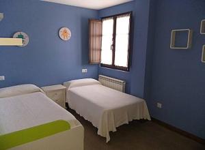 a blue room with two beds and a window at LOS LAURELES in Cudón