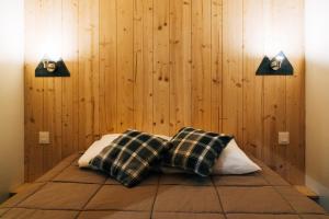 ein Bett mit zwei Kissen in einem Zimmer mit Holzwänden in der Unterkunft Azun Nature in Aucun
