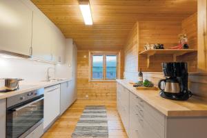 a kitchen with white cabinets and a wooden wall at Guesthouse / Huskyfarm Innset in Innset
