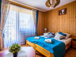 a bedroom with a bed with blue sheets and a window at Noclegi u Jancoka in Brzegi