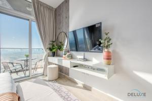 a white living room with a television and a balcony at Precious Studio at Bloom Towers JVC by Deluxe Holiday Homes in Dubai