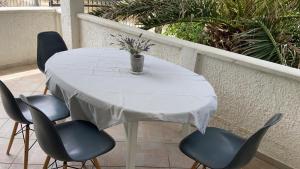 Biały stół z 4 krzesłami i wazonem na nim w obiekcie Oguic apartman w mieście Pag