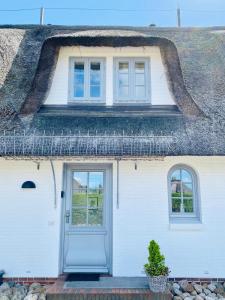 a white house with a thatched roof with a blue door at Sylt-Traum Möwe in Keitum