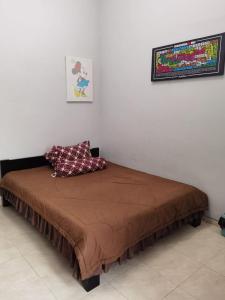 ein Bett mit einer braunen Tagesdecke und einem Bild an der Wand in der Unterkunft Villa Pesanggrahan Kusuma Batu in Batu