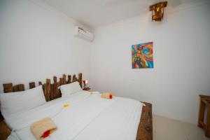 uma cama branca num quarto com uma pintura na parede em Maisha Matamu Beach Hotel Paje em Paje