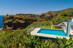 a house with a swimming pool next to the ocean at Sonho do Oceano in Ribeira Brava