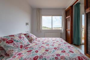 1 Schlafzimmer mit einem Bett mit Blumenbettdecke und einem Fenster in der Unterkunft Casa Creu Mar in Sant Feliu de Guixols