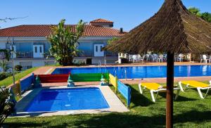 a pool with an umbrella and chairs and a building at APARTHOTEL CABICASTRO Tres estrellas superior in Portonovo