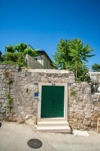 une porte de garage verte sur un mur en pierre dans l'établissement Garden Apartment Hotel, à Split