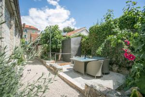 un patio con mesa y sillas en un jardín en Garden Apartment Hotel, en Split