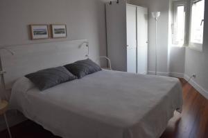 um quarto com uma grande cama branca e 2 almofadas em Apartamento cerca de la playa em Santander