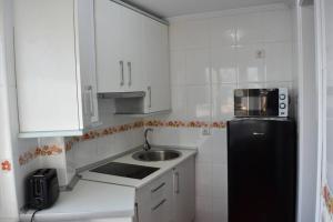 a small kitchen with a sink and a black refrigerator at Apartamento cerca de la playa in Santander +2 photos