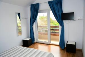 a bedroom with a bed and a window with blue curtains at Pensiunea Codalb in Jurilovca