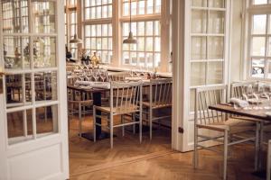 ein Esszimmer mit einem Tisch, Stühlen und Fenstern in der Unterkunft Arnbjerg Pavillonen in Varde