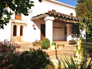 une maison blanche avec des plantes en pot devant elle dans l'établissement Sera de Vall, à Bahía de Sant Antoni