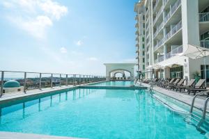 a swimming pool with chairs and a building at Sea it All Infinity pool ocean views steps from the beach - a perfect romantic getaway in Galveston