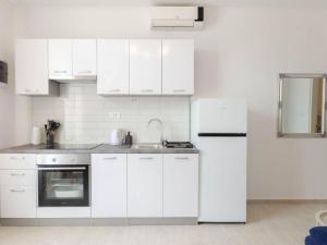 Biała kuchnia ze zlewem i lodówką w obiekcie Apartments K & N w mieście Prižba