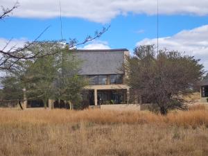 a house in the middle of a field with trees at Zebula 5 Bedroom, sleeps12 IZN1 in Mabula